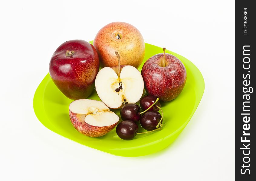 Red big Apple and Cherry on green plate isolated on white background