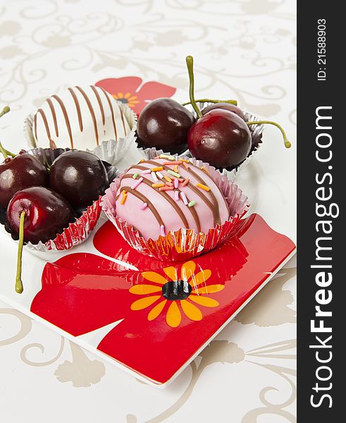 Cup of donuts and Cherry in beautiful flower plate on mat