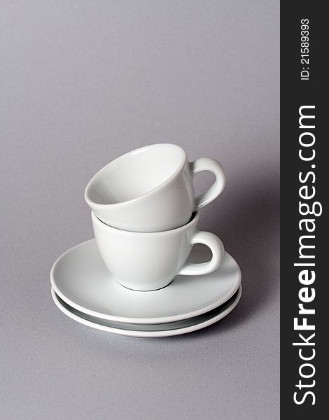 Two teacups neatly stacked for storage on a gray background. Two teacups neatly stacked for storage on a gray background