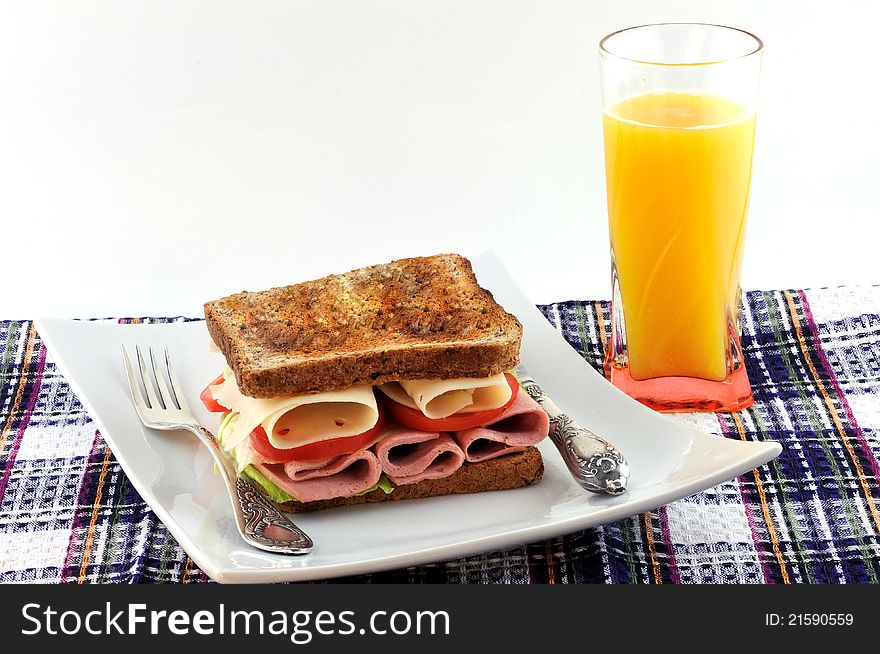 Toasted bread, cheese, tomatoes and sausage on a plate and a glass of orange juice. Toasted bread, cheese, tomatoes and sausage on a plate and a glass of orange juice