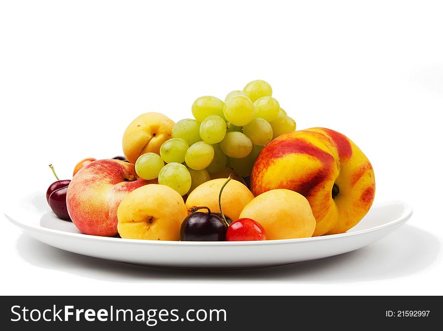 Grapes, peaches, cherries, sweet cherries on a plate on a white background. Grapes, peaches, cherries, sweet cherries on a plate on a white background
