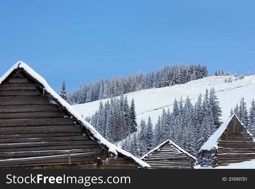 Winter background with roofs of houses and slopes of mountains. Ukraine, Carpathians