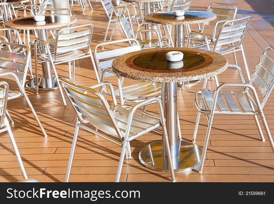 Tables with ashtrays in outdoor bar on stern of cruise liner