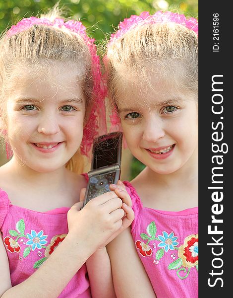 Shot of twin girls sharing a cell phone call vertical