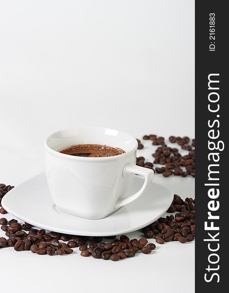White coffee cup on a plate and coffee beans. White coffee cup on a plate and coffee beans