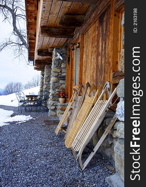 Old wooden sledges in front a typical chalet in the alps. Old wooden sledges in front a typical chalet in the alps