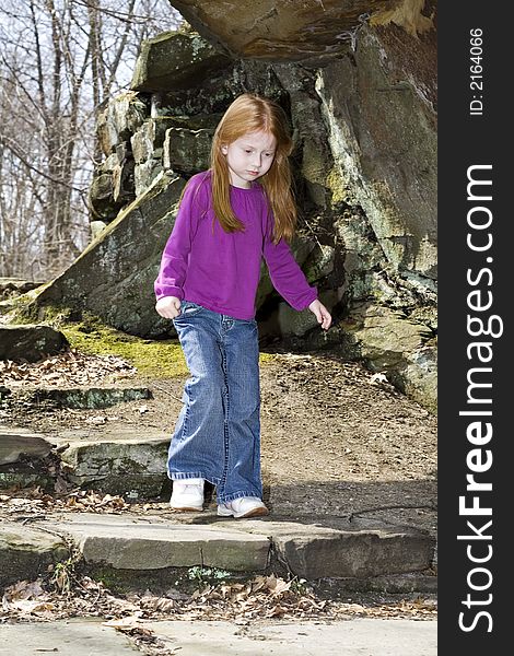 A small red-head girl explores a new park in the spring. A small red-head girl explores a new park in the spring.