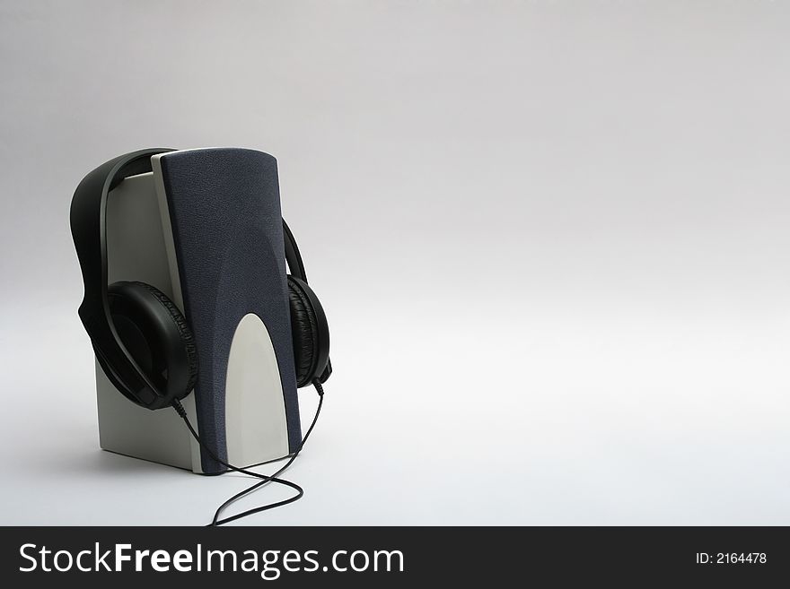 Single speaker with a headphones hanging on it. Single speaker with a headphones hanging on it