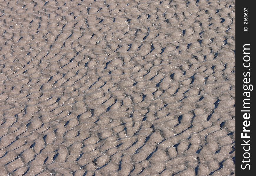 Dark sand with wave marks from the sea. Dark sand with wave marks from the sea