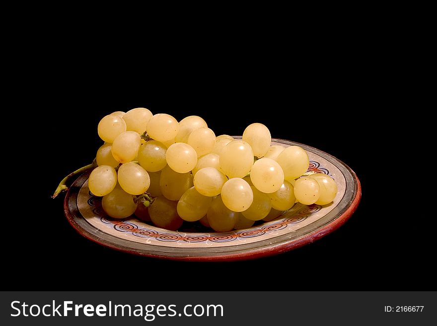 A bunch of white grapes on a plate, isolated on black
