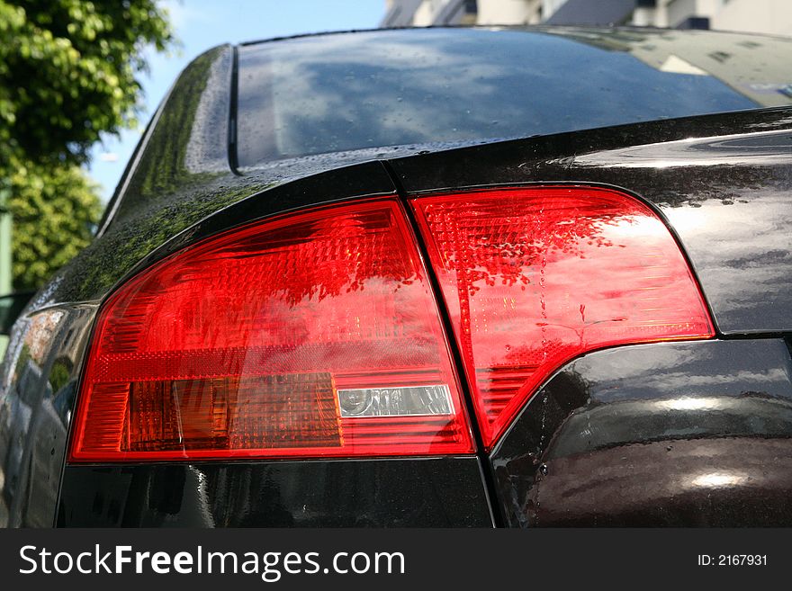 Back lights of a sport black car in blue sky. Back lights of a sport black car in blue sky