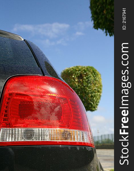 Back lights of a sport black car in blue sky. Back lights of a sport black car in blue sky