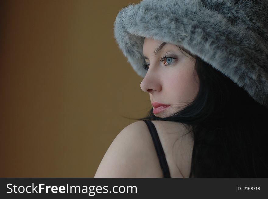 Black-haired girl with a fur hat on a brown background. Black-haired girl with a fur hat on a brown background