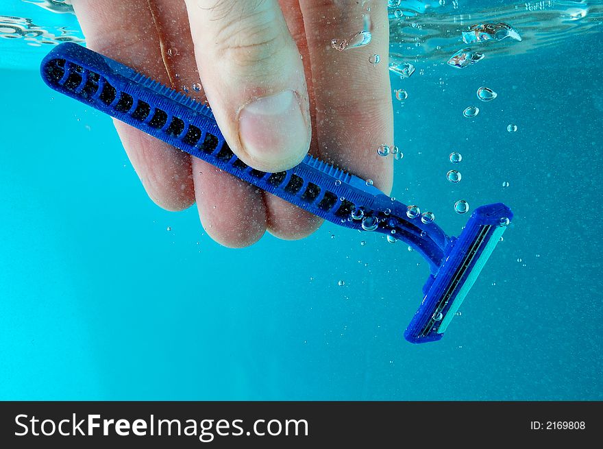 A hand cleaning razor in water - blue background