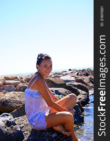 The girl sitting on a stone at the sea also swims in the dreams