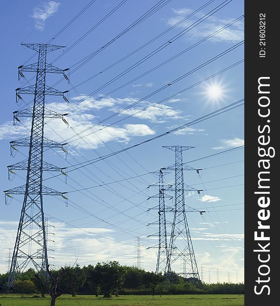 The tower of high voltage line with blue sky and sun.