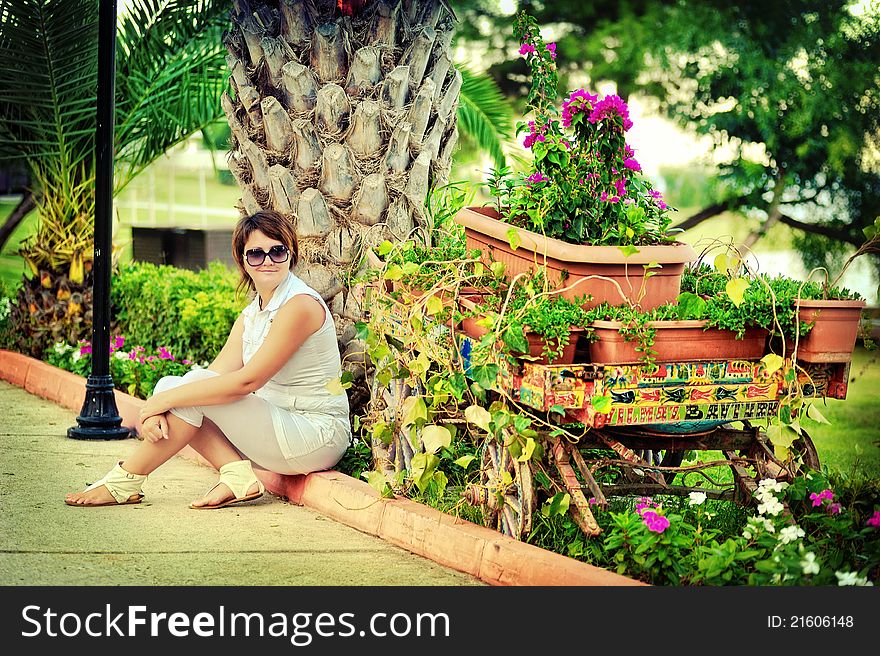 The girl in park in the summer on avenue between bushes of greens wearing spectacles