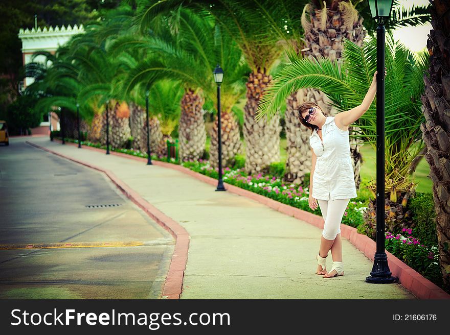 The girl in park in the summer on avenue between bushes of greens wearing spectacles