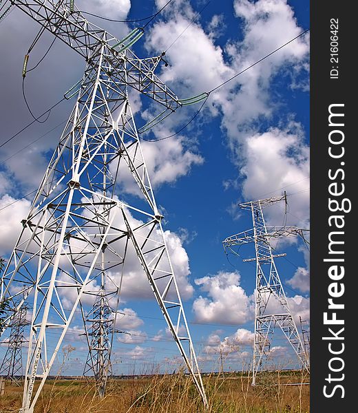 Masts of electric mains and cloudy sky