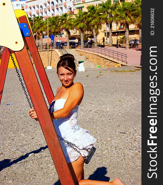 The girl sits on a swing on one of beaches of a resort city. The girl sits on a swing on one of beaches of a resort city