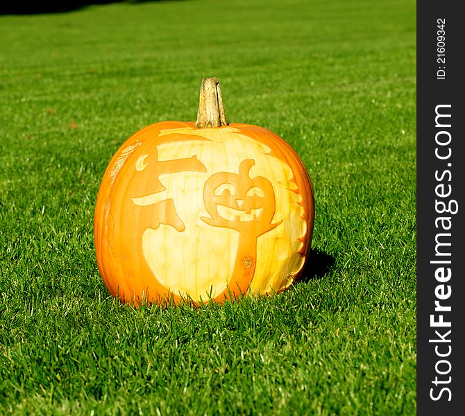 Picture of a pumpkin, with silhouette of a witch and a pumpkin cut in the surface. Standing on a lawn. Picture of a pumpkin, with silhouette of a witch and a pumpkin cut in the surface. Standing on a lawn