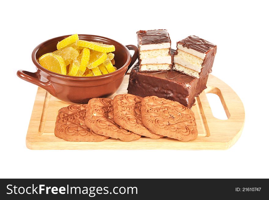 Fruit candy, cake, cookies lie on a wooden board. Fruit candy, cake, cookies lie on a wooden board