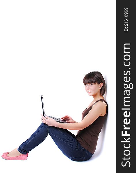 Pretty woman sitting against wall with laptop
