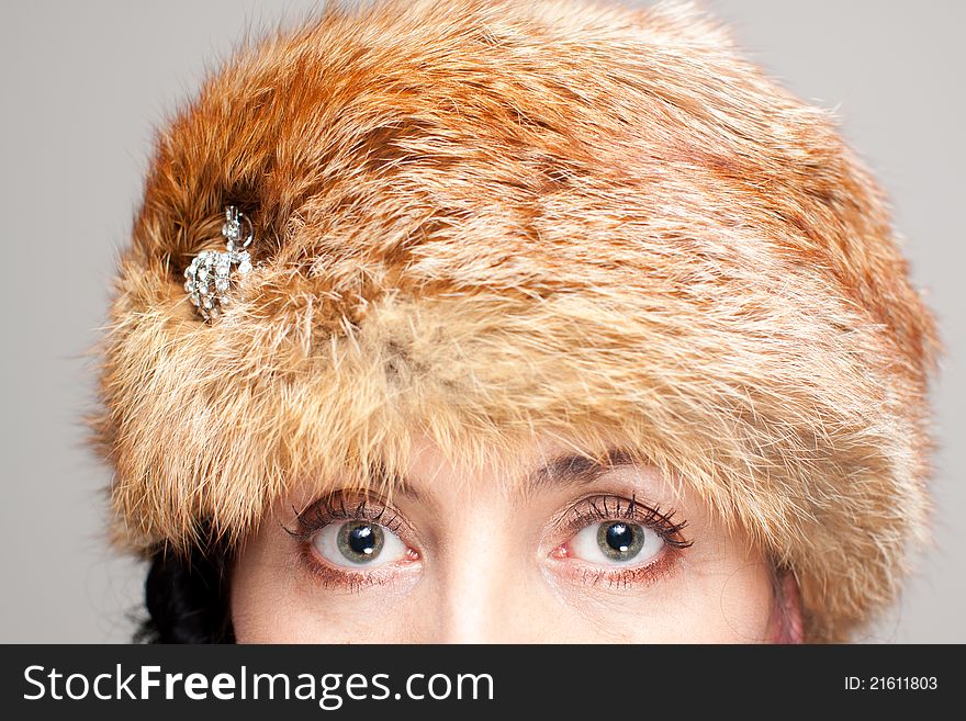 Mature brunette in d fox hat on gray background. Intents look. Mature brunette in d fox hat on gray background. Intents look