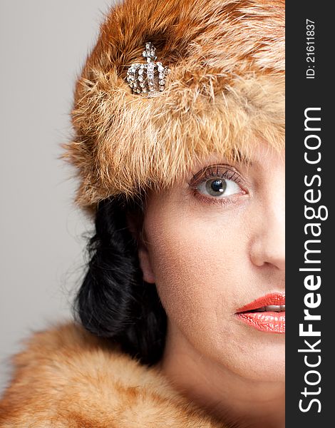 Closeup of Mature brunette in fox hat on gray background. Intents look and red lips. Closeup of Mature brunette in fox hat on gray background. Intents look and red lips