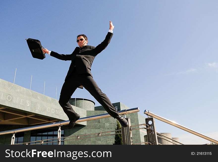 Young handsome businessman jumping in the street