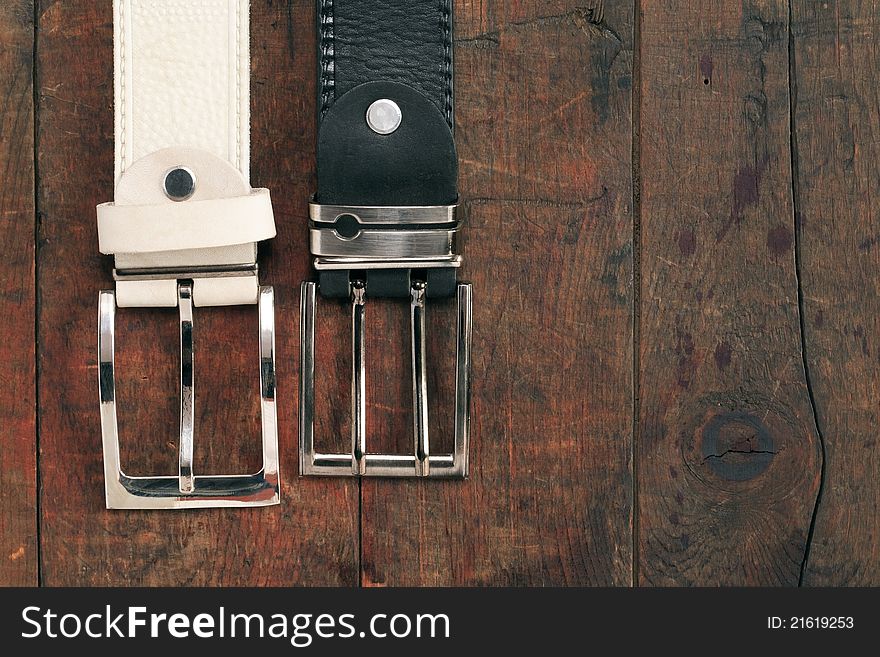 White and black leather belts hanging on old wooden background. White and black leather belts hanging on old wooden background