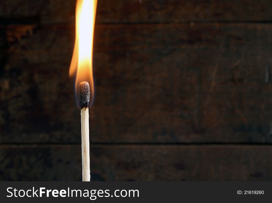 Closeup of one burning match on dark background