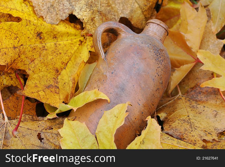 Vintage ceramic bottle in the middle of the fallen maple leaves. Vintage ceramic bottle in the middle of the fallen maple leaves