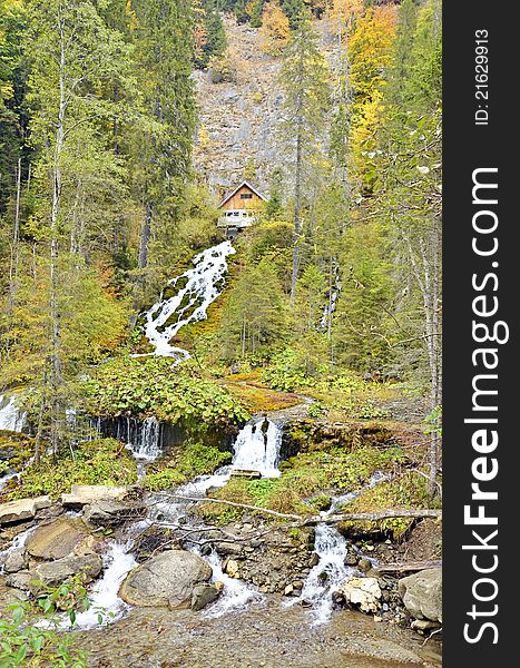 Waterfall in the mountain forest and wooden cottage. Waterfall in the mountain forest and wooden cottage