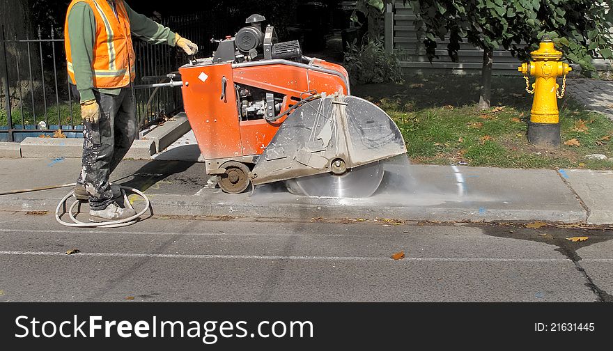 Worker with stonecutting equipment on residential street. Worker with stonecutting equipment on residential street