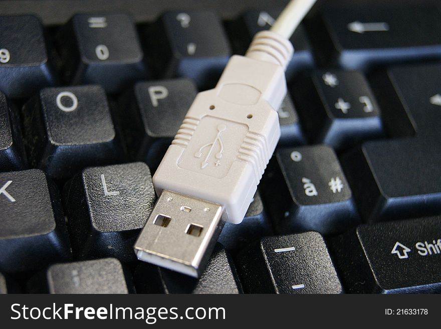 White USB cable on a black keyboard. White USB cable on a black keyboard