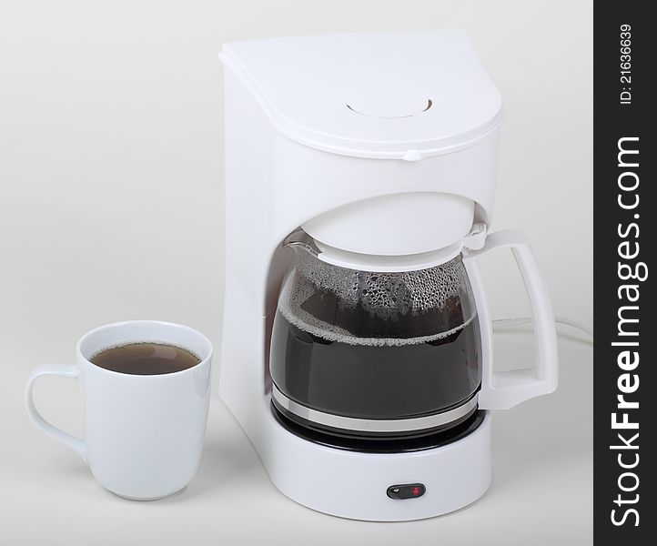 Cup of coffee next to a coffee maker on a white background. Cup of coffee next to a coffee maker on a white background