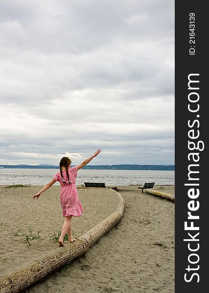 Young Girl Balancing On Log At Beach