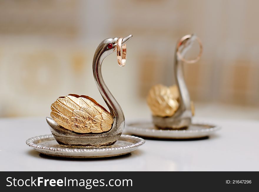 Two gold wedding rings on beautiful swans