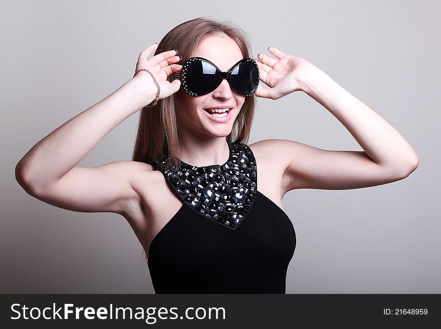 Fashion woman in a stylish glasses on gray background