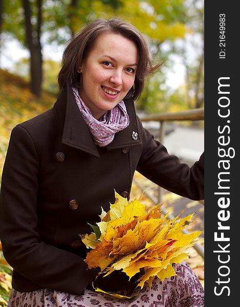 Lovely woman smiling with autumn leaves