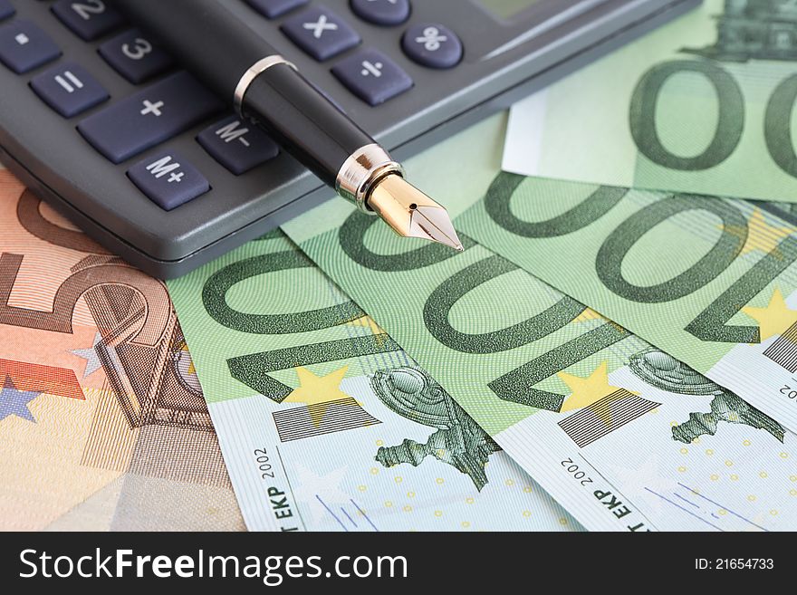 Business concept. Closeup of fountain pen and calculator on european currency background. Business concept. Closeup of fountain pen and calculator on european currency background