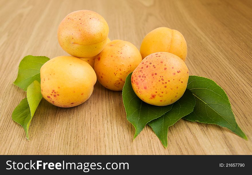 Apricots with leaves on the table .