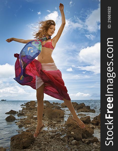 Girl jumping on a beach in bright clothes against the backdrop of the ocean. Girl jumping on a beach in bright clothes against the backdrop of the ocean