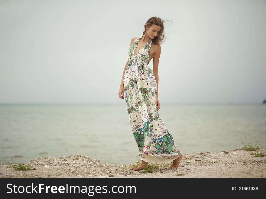 Young girl walking along the beach, the wind blows dress