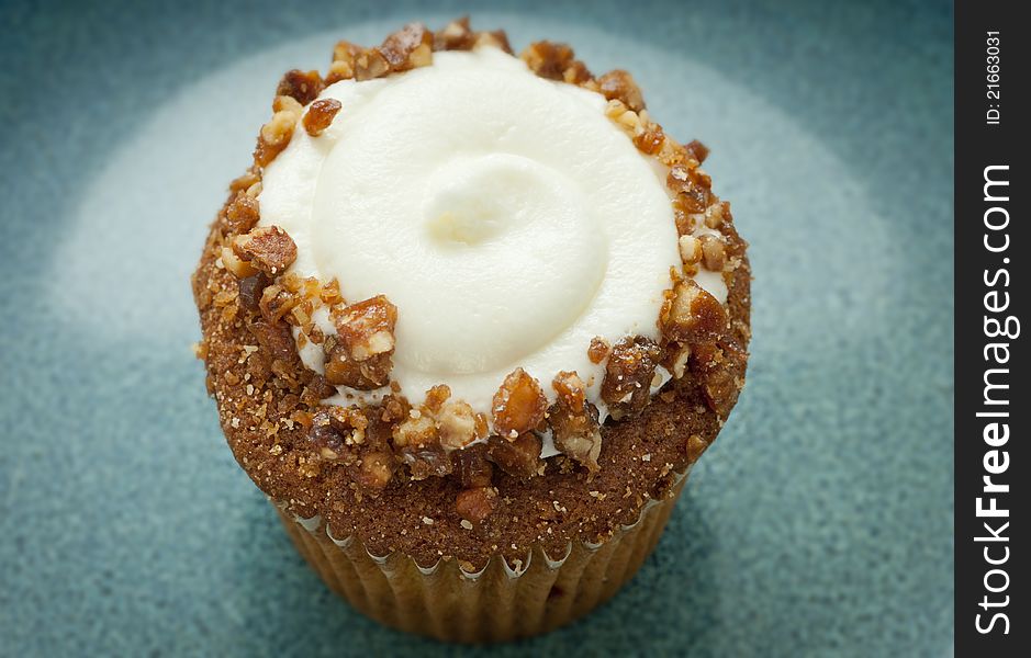 Carrot muffin with nuts and vanilla  buttercream on green plate. Carrot muffin with nuts and vanilla  buttercream on green plate