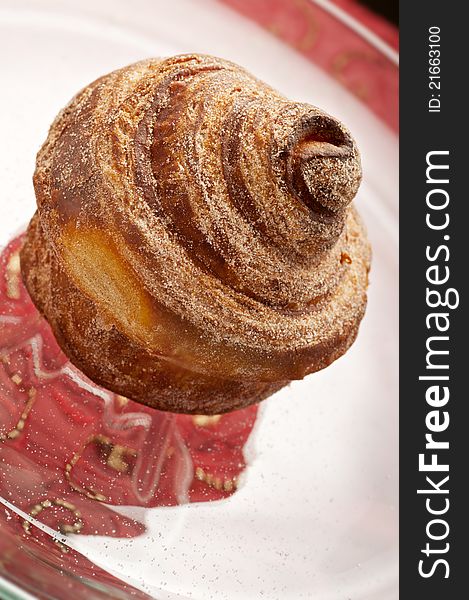 Baked cinnamon bun on glass display plate. Baked cinnamon bun on glass display plate