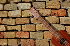 Photography Of Ukulele With Brick Wall In The Background Royalty Free Stock Images