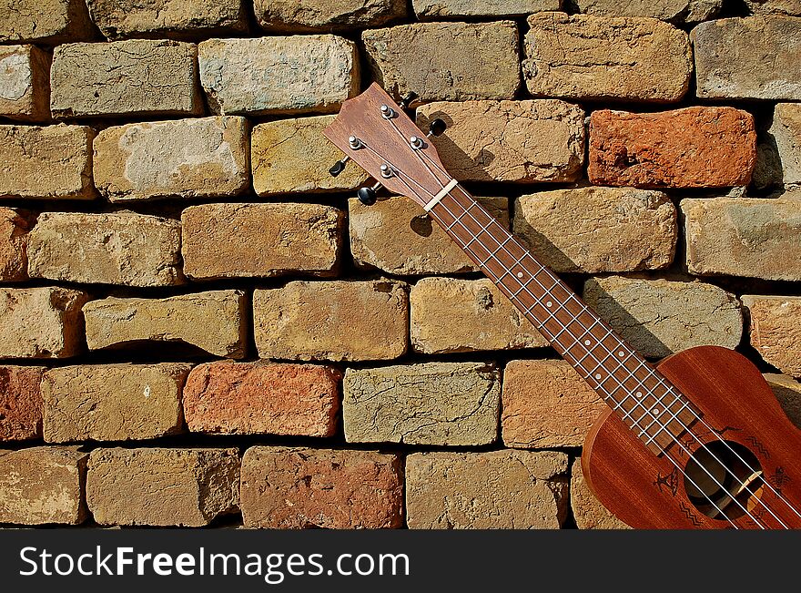 Photography of ukulele with brick wall in the background