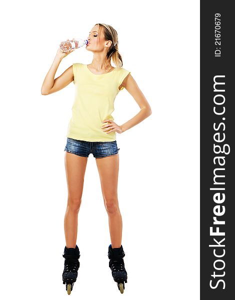 Pretty sporty girl in roller skates drinking mineral water